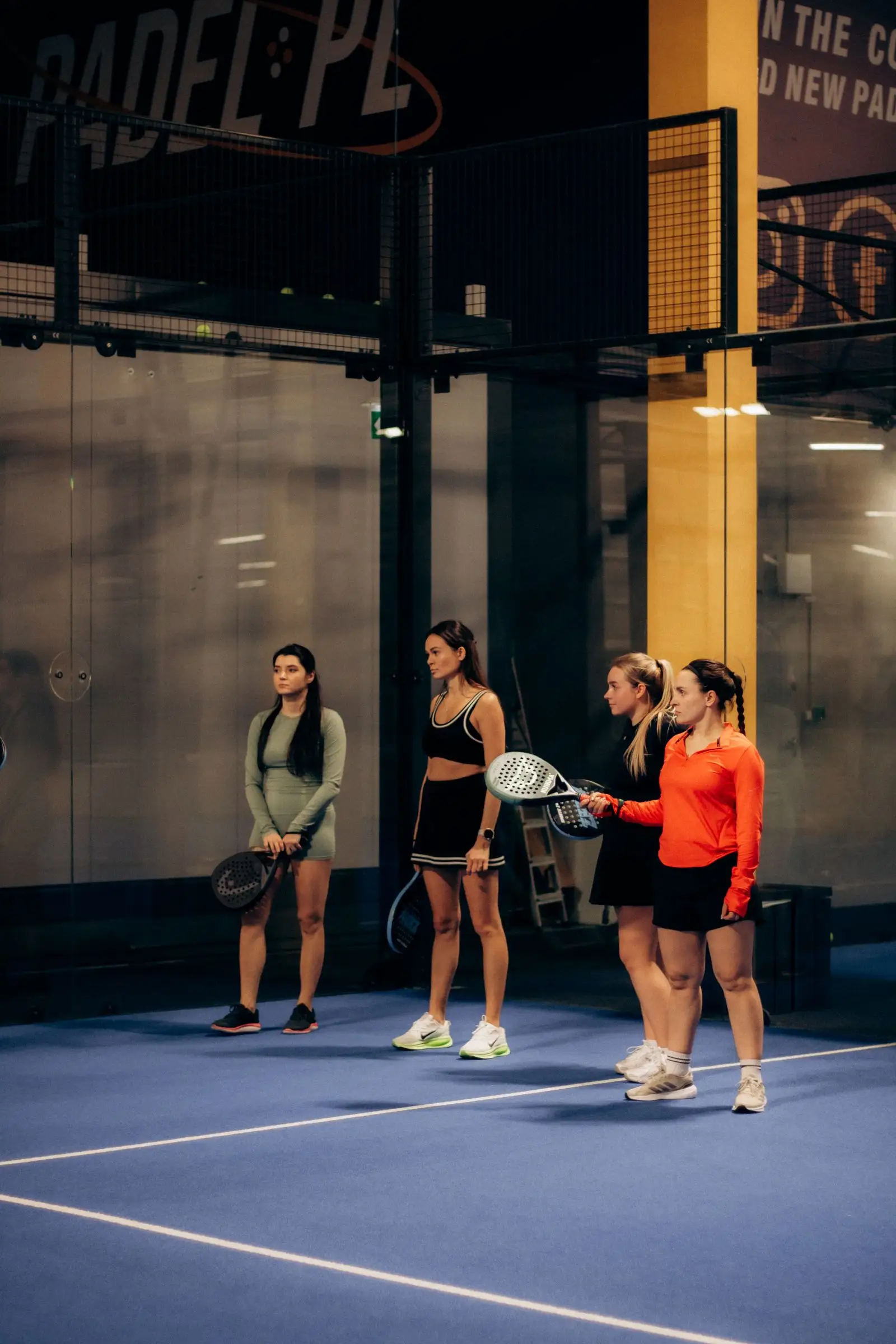 Quatre joueuses de padel prêtes à jouer, raquettes en main