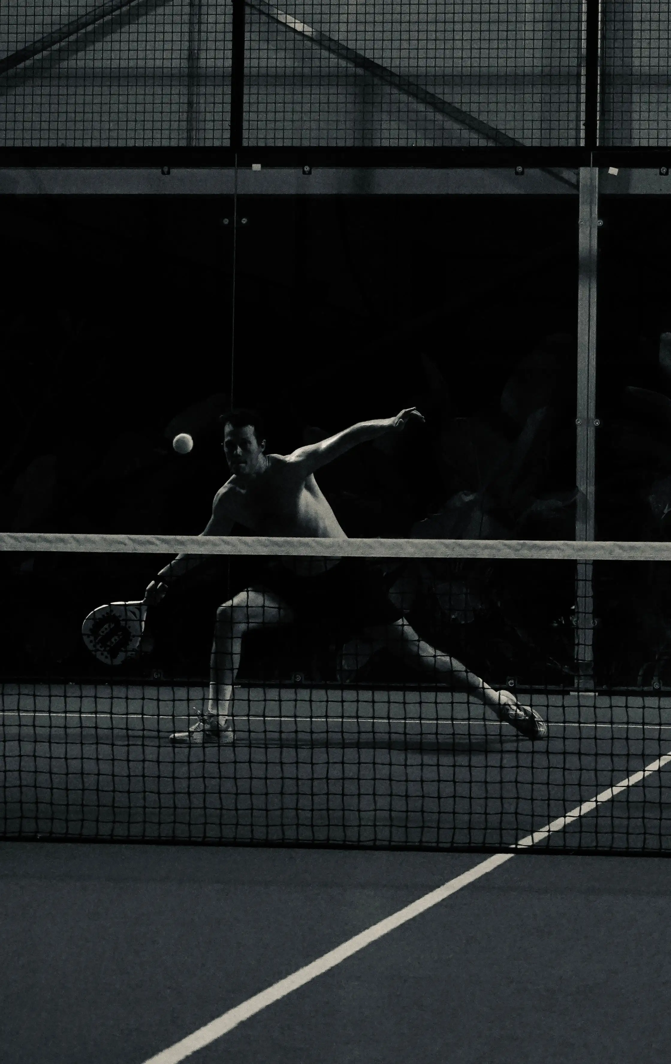 Un joueur de padel plonge sur une balle pendant un match de nuit